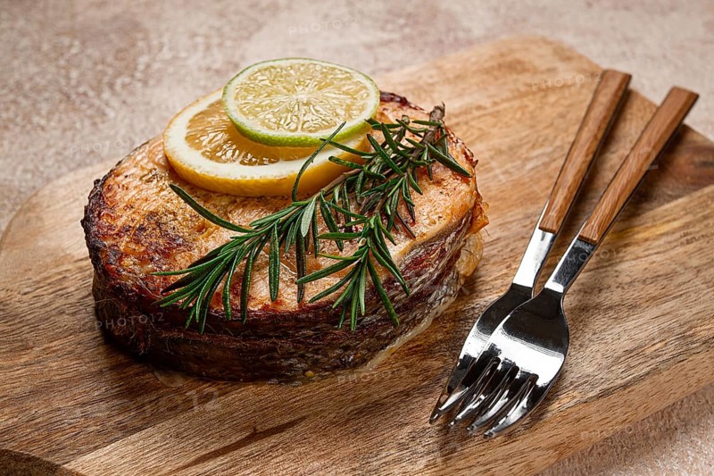 Salmon steak, fried, on a cutting board, top view, rosemary, lemon and lime, homemade, one serving, no people