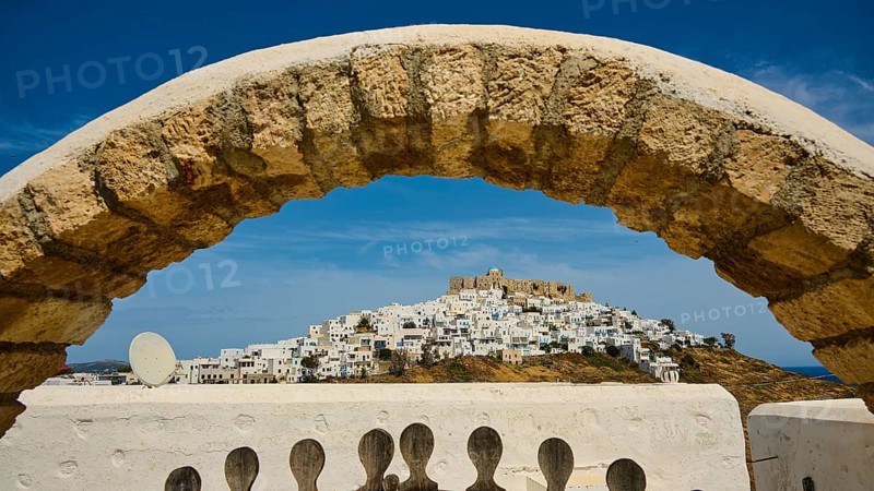 Stone arch frames the view of a hilltop village with a fortress, Querini Castle, Chora, Astypalea, Dodecanese, Greek Islands, Greece, Europe