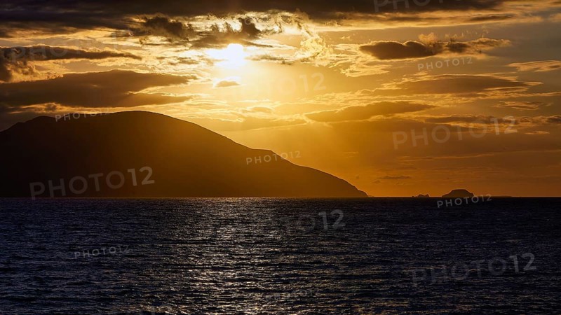 Dramatic sunset over the sea, island visible as a silhouette, Kassos island, neighbouring island Karpathos, Dodecanese, Greek Islands, Greece, Europe