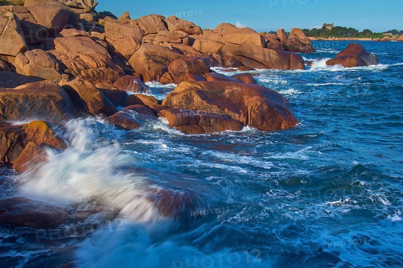 Large rocks on the Granit Rose coast, lapped by the dynamic waves of the blue sea, Ploumanach, Cote De Granit Rose, Cotes-d Armor department, Bretange, France, Europe