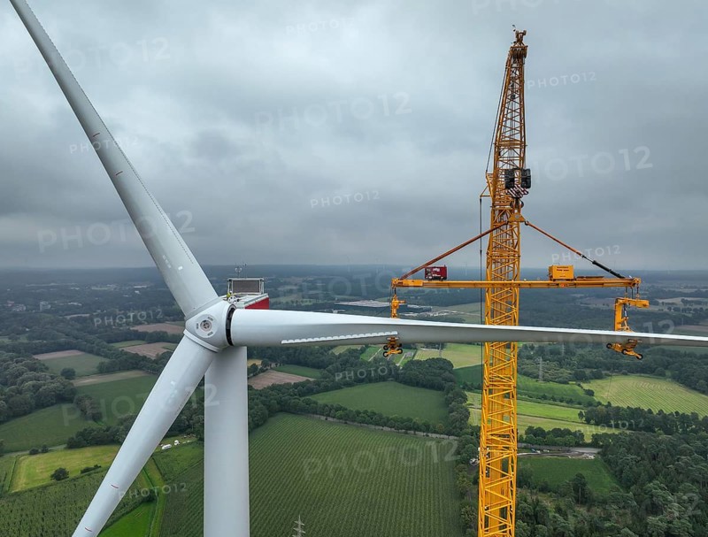 Dorsten, North Rhine-Westphalia, Germany, construction of a wind turbine. A large mobile crane lifts a rotor blade to the nacelle on the tower. Here, the blade is mounted directly on the motor hub. Große Heide wind farm, Europe