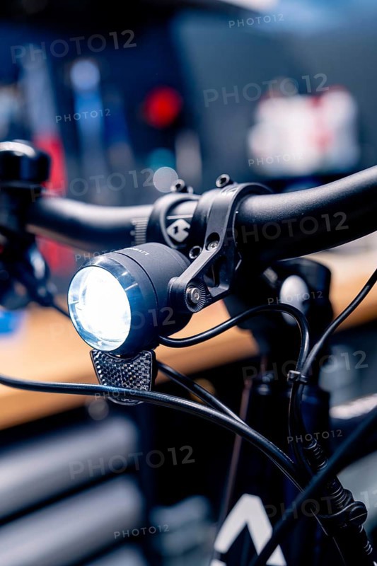 Bicycle light on the handlebars shines brightly in a workshop, focus on technological details, Waldbike Manufaktur, bicycle workshop, Calw, district of Calw, Black Forest, Germany, Europe