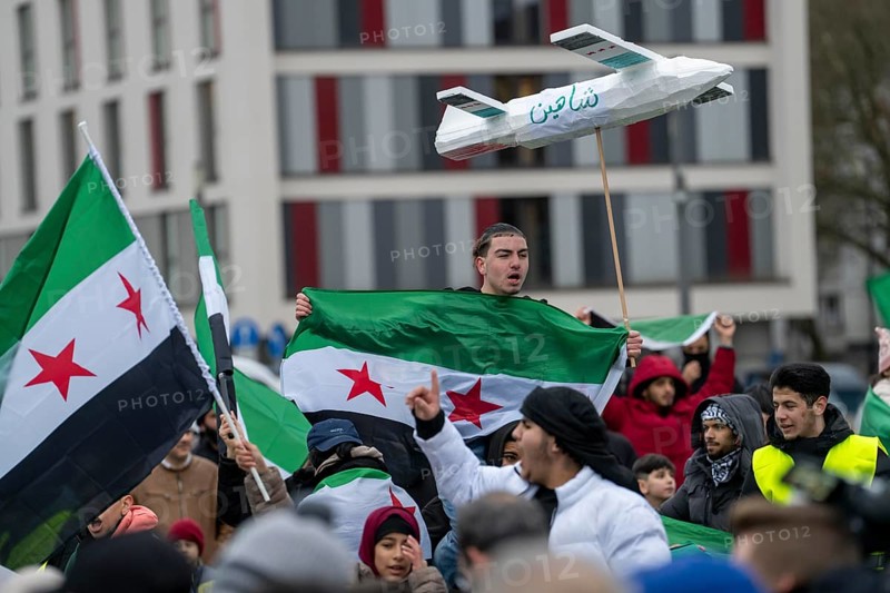 People celebrate the end of the Assad regime after the change of power in Syria at a rally on the square in front of the main railway station in Duisburg, North Rhine-Westphalia, Germany, Europe