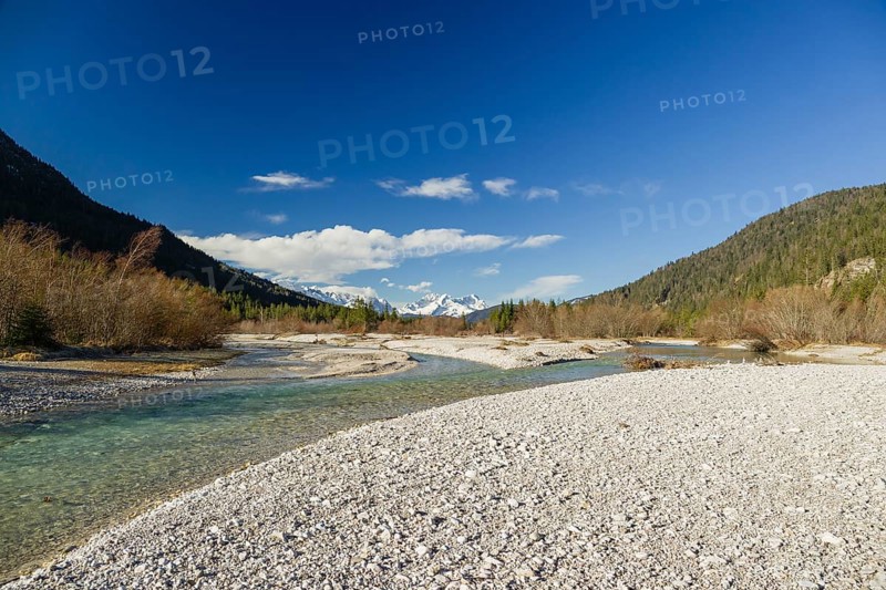 Isar valley nature conservancy area on an early sunny morning. The wild Isar river flows through its gravel bed past driftwood and entrained trees and bushes