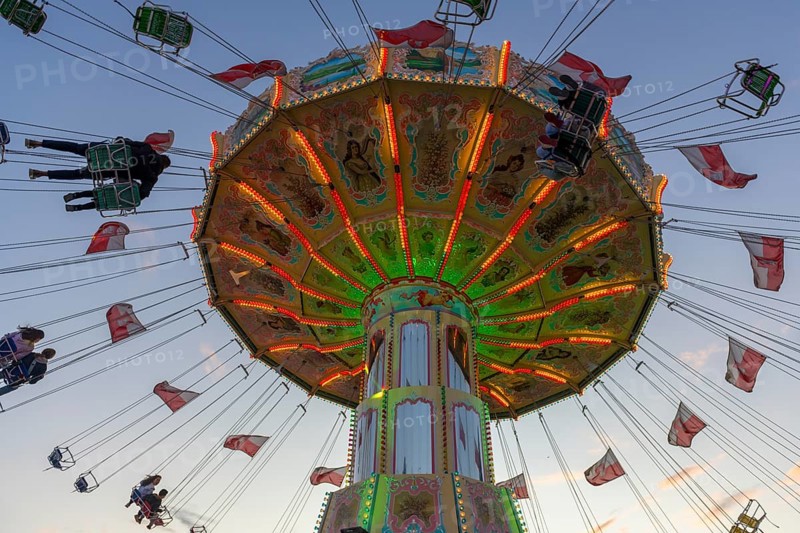A colourfully illuminated carousel with swinging seats against an evening sky, wave flight, chain carousel, Bad Cannstatt, Stuttgart, Baden-Württemberg, Germany, Europe