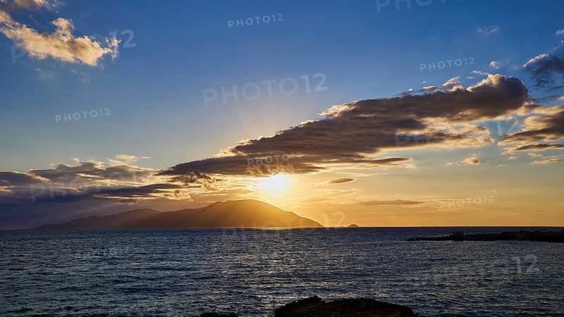 Dramatic sunset over the sea with clouds and island on the horizon, rays in the sky, sunset, Kassos, Karpathos, offshore islands, Dodecanese, Greek Islands, Greece, Europe