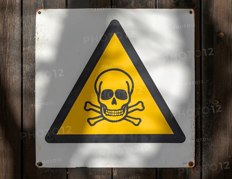 Black triangular yellow infill skull and cross bones danger of death warning sign, UK