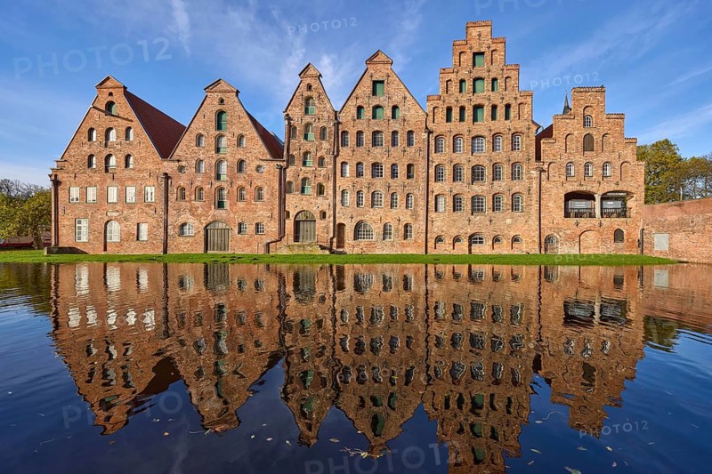 Historic salt warehouses with reflections on the water surface of the Trave, blue sky with veil clouds, Hanseatic city of Lübeck, Schleswig-Holstein, Germany, Europe