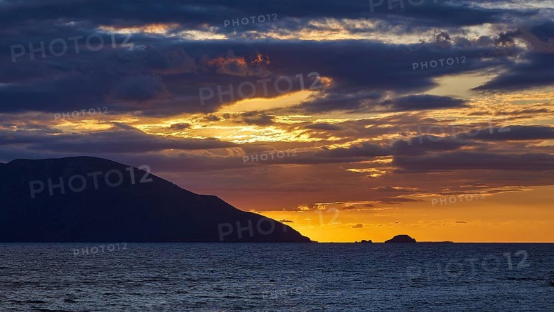 Sunset over the sea with dark clouds and silhouette of the mountains on the horizon, sunset, Kassos, Karpathos, offshore islands, Dodecanese, Greek Islands, Greece, Europe