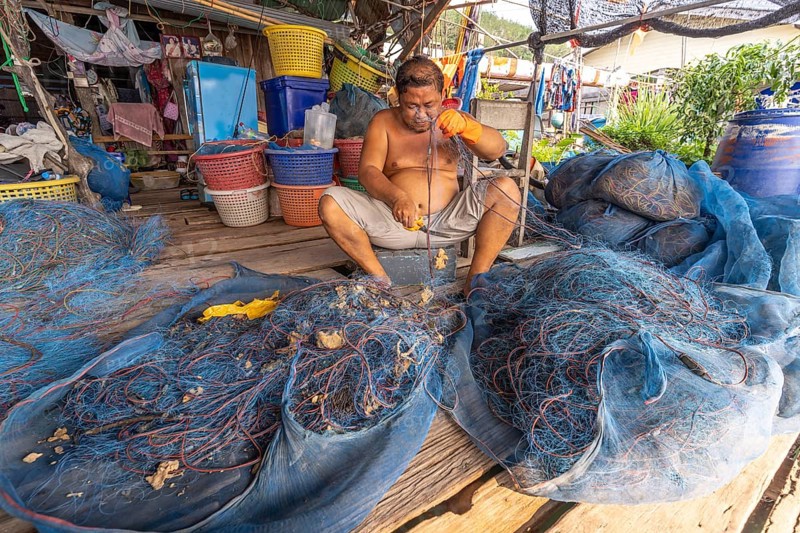 Fisherman repairing his net, fishing village Ban Ao Salad, island Ko Kut or Koh Kood in the Gulf of Thailand