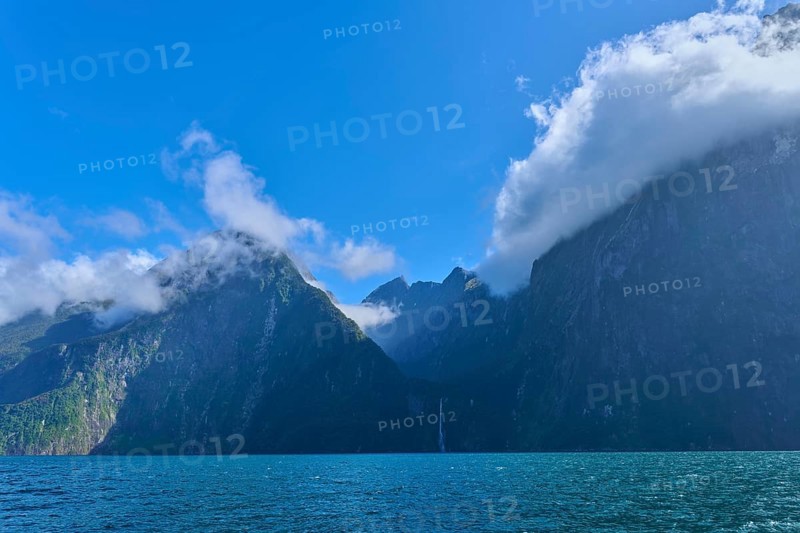 Twisted clouds envelop majestic mountains over the sea, fjord landscape, summer, Milford Sound, Te Anau, Fiordland National Park, South Island, New Zealand, Oceania