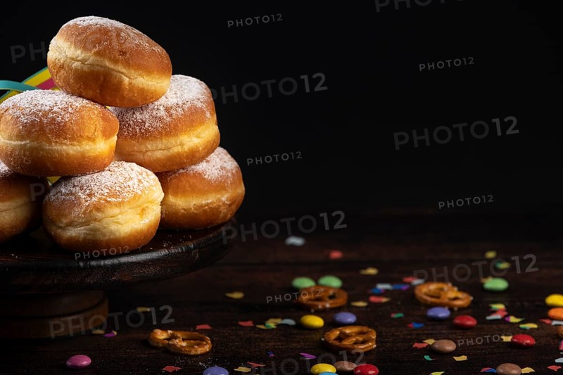 Doughnuts on a plate with scattered confetti and pretzels on a dark background