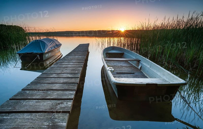 Quiet lake at sunset, rowing boats moored in the water at a wooden jetty, Gudelacksee, Lindow, Brandenburg, Germany, Europe