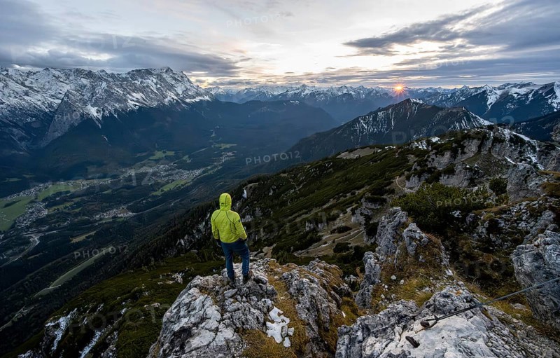View Mountain panorama with Wetterstein mountains and Zugspitze, at sunset with sun star, mountaineer at the summit of the Kramerspitz, in autumn, Ammergau Alps, in autumn, Bavarian Prealps, Bavaria, Germany, Europe