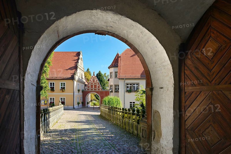 View through the castle gate of Wiesenburg Castle to the houses of the historic old town, Wiesenburg, Hoher Fläming nature park Park, Brandenburg, Germany, Europe