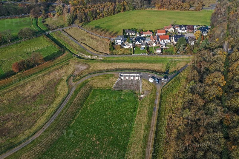 10.11.2021, Datteln, North Rhine-Westphalia, Germany - Flood protection during heavy rainfall by rainwater retention basin, rainwater retention basin RRB with storage channel SKU Gutacker on the Dattelner Mühlenbach, behind residents in the Zum Gutacker housing estate. Following the construction of a parallel sewer, the Dattelner Mühlenbach is now free of wastewater, is part of the Lippe river system and was previously an open, above-ground wastewater sewer, combined sewer with surface water and wastewater
