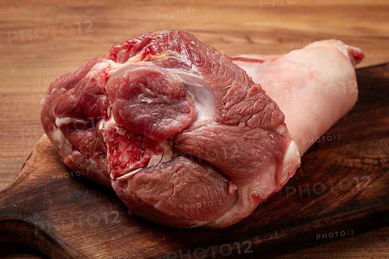 Raw pork knuckle, on a wooden chopping board, close-up, top view, no people