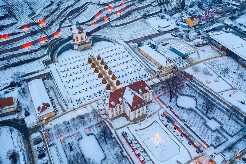 Aerial view of Wackerbarth Castle with castle park, belvedere and vineyards with snow and Christmas lights, Radebeul, Saxony, Germany, Europe