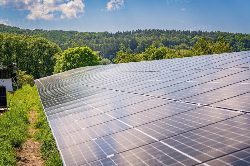 Large solar panels on a field reflecting the sun's rays, surrounded by trees and sky, construction of the Black Forest Nature solar park, Weil der Stadt, Germany, Europe