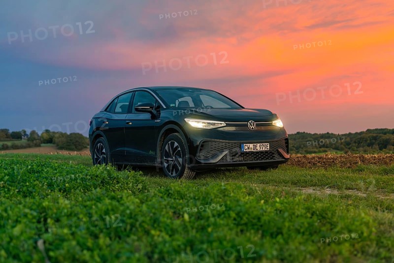 A car stands in front of a dramatic sunset in a field with a colourful sky, electric car, VW ID5, Gechingen, Black Forest, Germany, Europe