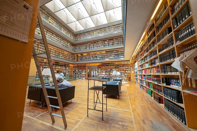 Large modern library with well-stocked bookshelves, ladders and cosy reading area, Weimar, Germany, Europe