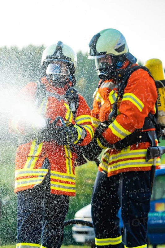 Two firefighters in full protective clothing spraying water with a fire hose, fire brigade, Enzklösterle, Black Forest, Germany, Europe