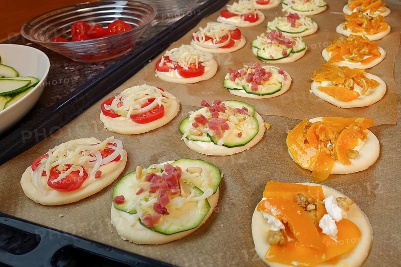 Swabian cuisine, preparation mini dinnete, also dennete, dinnede, dennetle, hearty, salty, yeast dough blanks, raw yeast dough with pumpkin, smoked meat, ham, roasted pine nuts, courgette slices, tomatoes, vegetables, sour cream, yeast pastry, bake, from the oven, typical Swabian reinterpreted, party pastry, finger food, appetisers for on the go, traditional cuisine, baking paper, oven tray, man's hand, food photography, studio, Germany, Europe