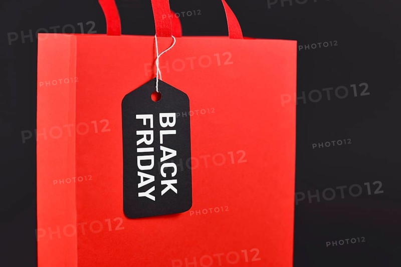 Black Friday sale label on red paper shopping bag on black background