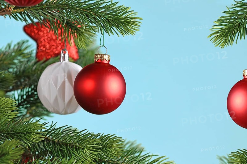 Red Christmas baubles on Christmas tree on blue background with copy space