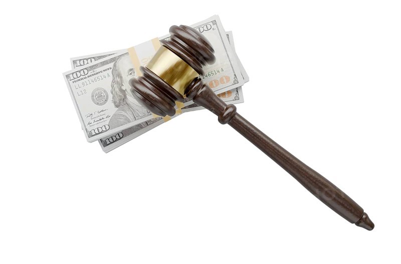 Overhead of gavel resting on stacks of thousands of dollars isolated on a white background