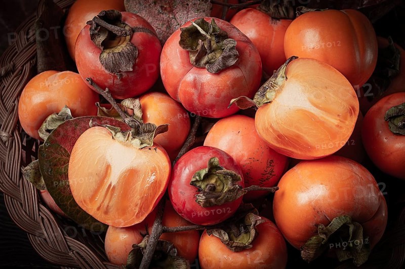 Fresh persimmon in a basket, with leaves, top view, no people