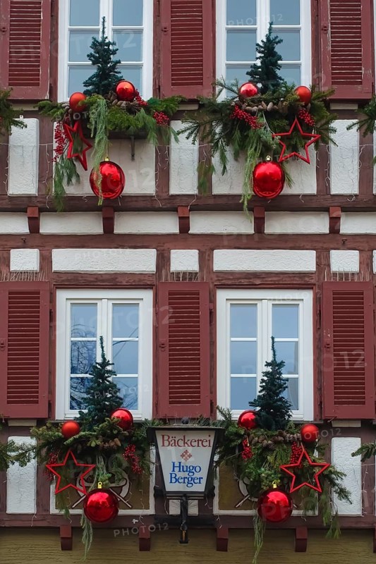 House facade with Christmas decoration, window, window shutters, half-timbered, Christmas motif, Christmas, Christmas festival, Advent season, red Christmas baubles, stars, fir trees, fir cones, conifer, fir branches, jewellery, Advent season, Christmas card motif, half-timbered house, lamp, lamp with writing, letters, Hugo Berger bakery, Reutlingen, Baden-Württemberg, Germany, Europe