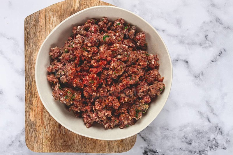 Raw minced meat, marinated with spices and herbs, in a bowl, minced meat with spices, top view, homemade, no people