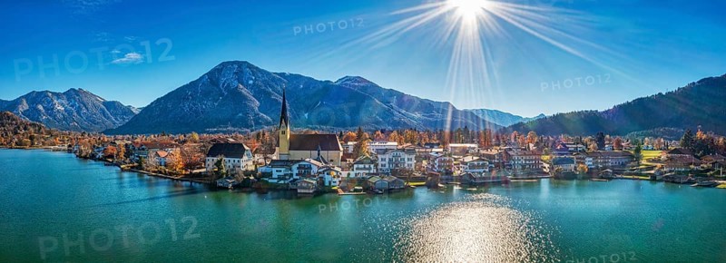 Panoramic shot of a village on the lake with mountains in the background, the sun shines on a clear blue sky, Rottach-Egern Tegernsee