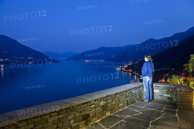 Woman Enjoy Panoramic View over Alpine Lake Maggiore with Mountain in Blue Hour in Ronco Sopra Ascona, Ticino, Switzerland, Europe