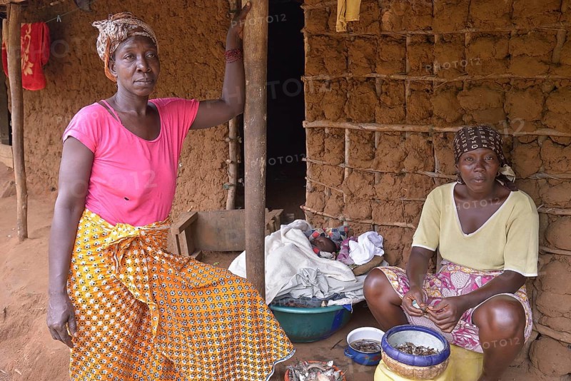 Two women in front of her mud hut, baby lying in a bowl between them, near Kent, Western Peninsula, Sierra Leone, Africa