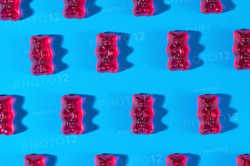 Red gummy bears in rows, on a blue background