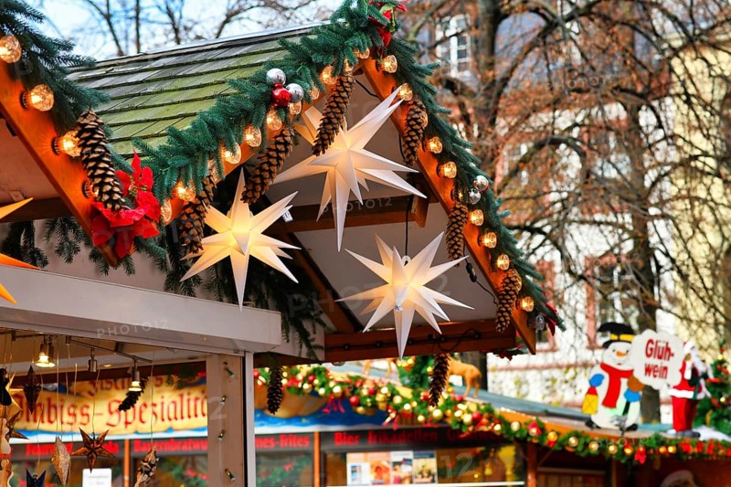 Heidelberg, Germany, November 2019: Seasonal decoration with fir branches, baubles and big paper stars on roof of sales stall during traditional Christmas market in city center of Heidelberg, Europe
