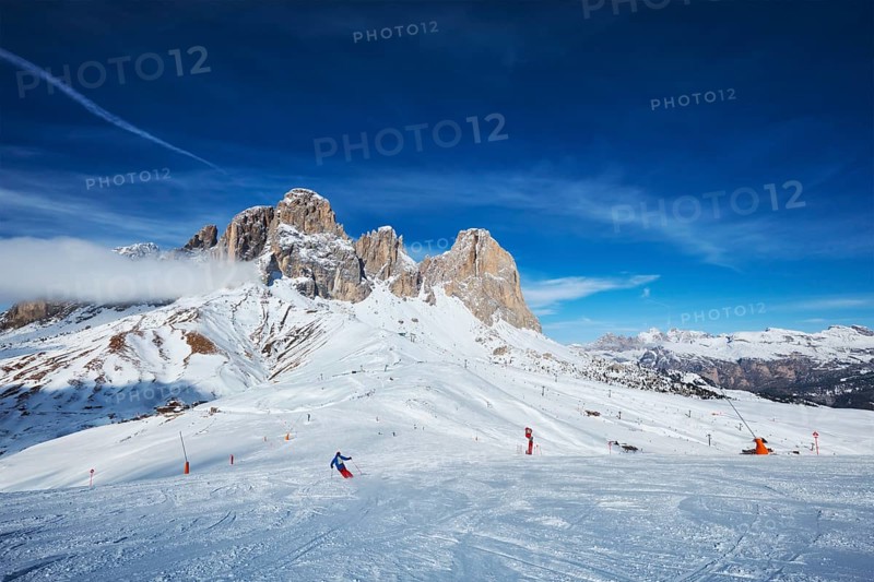 View of a ski resort piste with people skiing in Dolomites in Italy