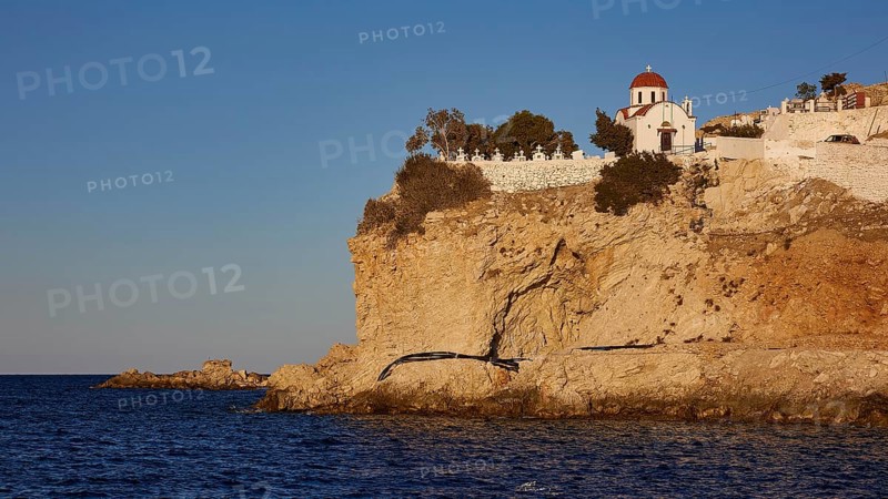 A small church on a rock above the sea in warm sunset light, Agios Nikolaos church, cemetery, Pigadia, town and harbour, Pigadia Bay, main town, Karpathos, Dodecanese, Greek Islands, Greece, Europe