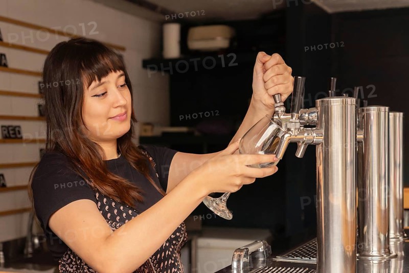 Young waitress with her hair pulled back serving beer at the bar in a restaurant