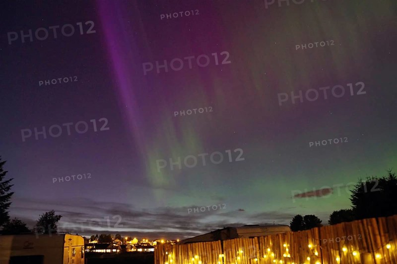 Northern Lights in the night sky above an illuminated fence and a campsite, Tönsberg, Oslofjord, Norway, Europe