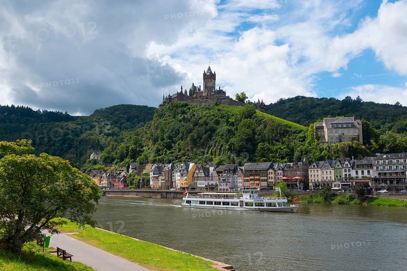 Lively town with a castle on a hill and ships on the river, surrounding green nature and clouds in the sky, Reichsburg, Cochem, Cochem-Zell, Moselle, Rhineland-Palatinate, Germany, Europe