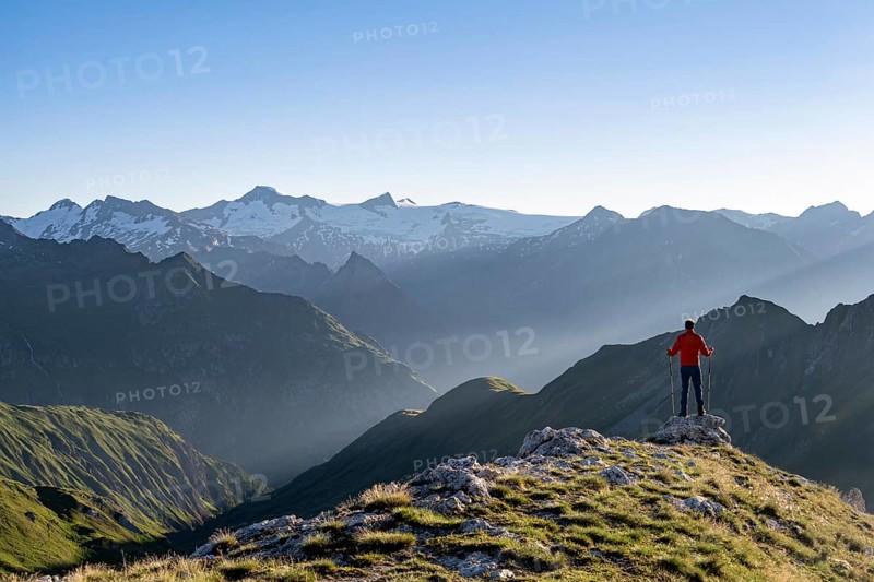 Mountaineer with poles on the summit of the Bachlenkenkopf at sunrise, atmospheric mountain panorama with the summit of the Großvenediger, Lasörling Group, Hohe Tauern National Park, East Tyrol, Austria, Europe