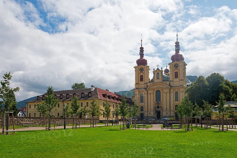 Baroque church with red roofs, surrounded by trees and green meadow with cloudy sky, monastery and pilgrimage church of the Visitation of Mary, Hejnice, Haindorf, Liberec, Czech Republic, Europe