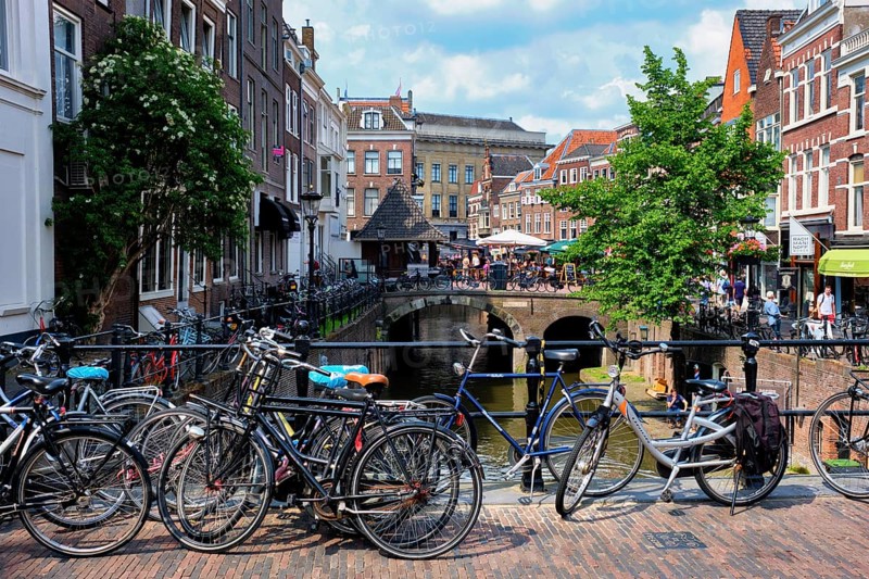 UTRECHT, NETHERLANDS, MAY 25, 2018: Bicycles which are a very popular transport in Netherlands parked in street along the canal near old houses. Utrecht, Netherlands