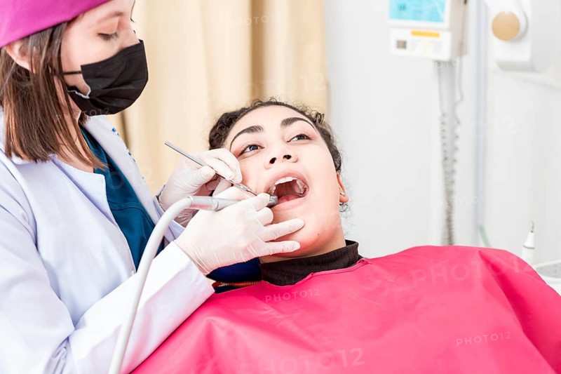View of a dentist cleaning a patient mouth with a drill. Stomatologist cleaning a patient's teeth, Close-up of a stomatologist cleaning a woman's teeth, Stomatologist cleaning caries with drill