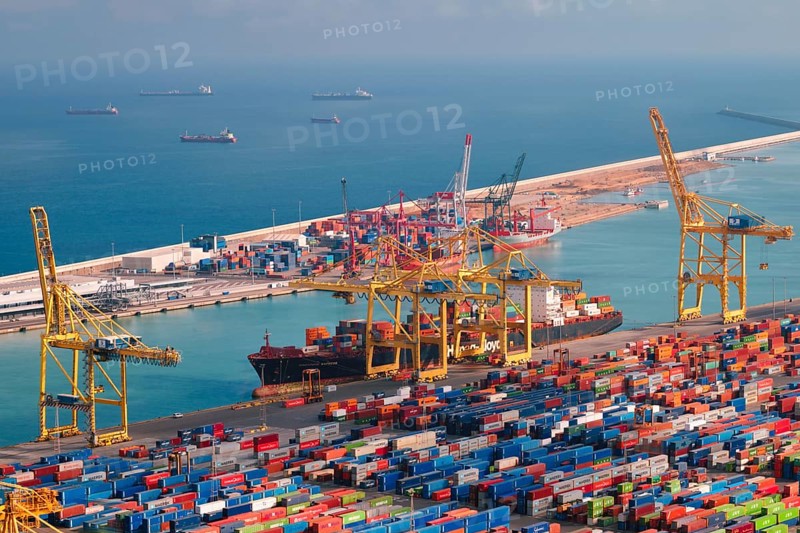 BARCELONA, SPAIN, APRIL 17, 2019: View of cargo ship unloading in Barcelona port terminal with straddle carrier trucks moving shipping containers