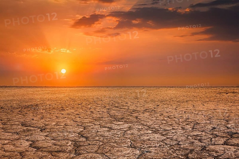 Global worming concept, cracked scorched earth soil drought desert landscape dramatic sunset