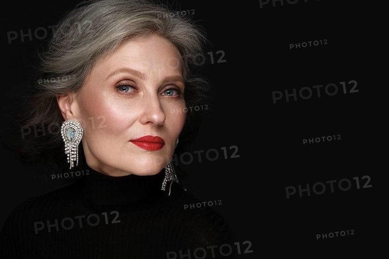 Portrait of a beautiful elderly woman in a white shirt with classic makeup and gray hair